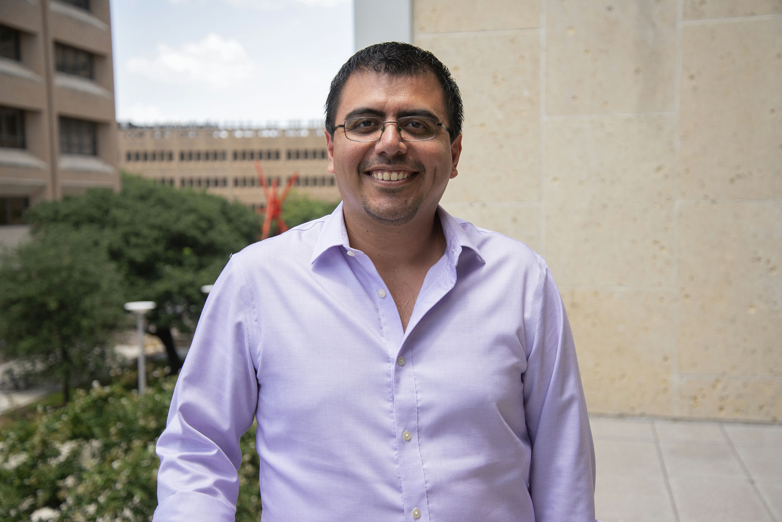 Pedro Santacruz in a purple shirt and glasses smiling.