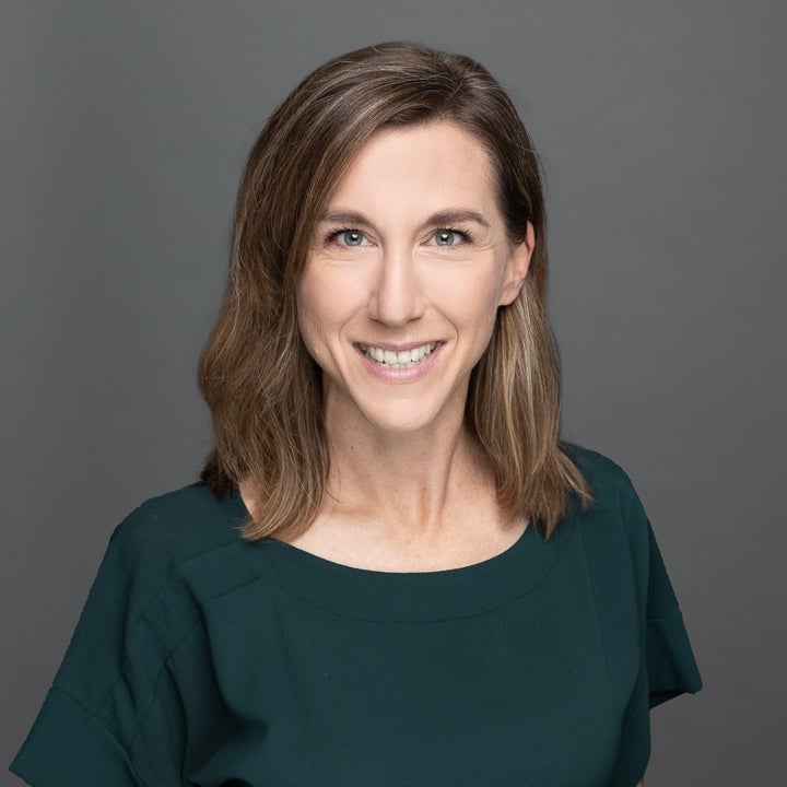 image of a white woman with dark brown hair, looking directly at the camera and smiling.