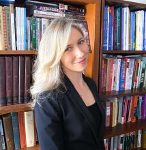 Headshot of Marina Alexandrova in front of a bookcase.  
