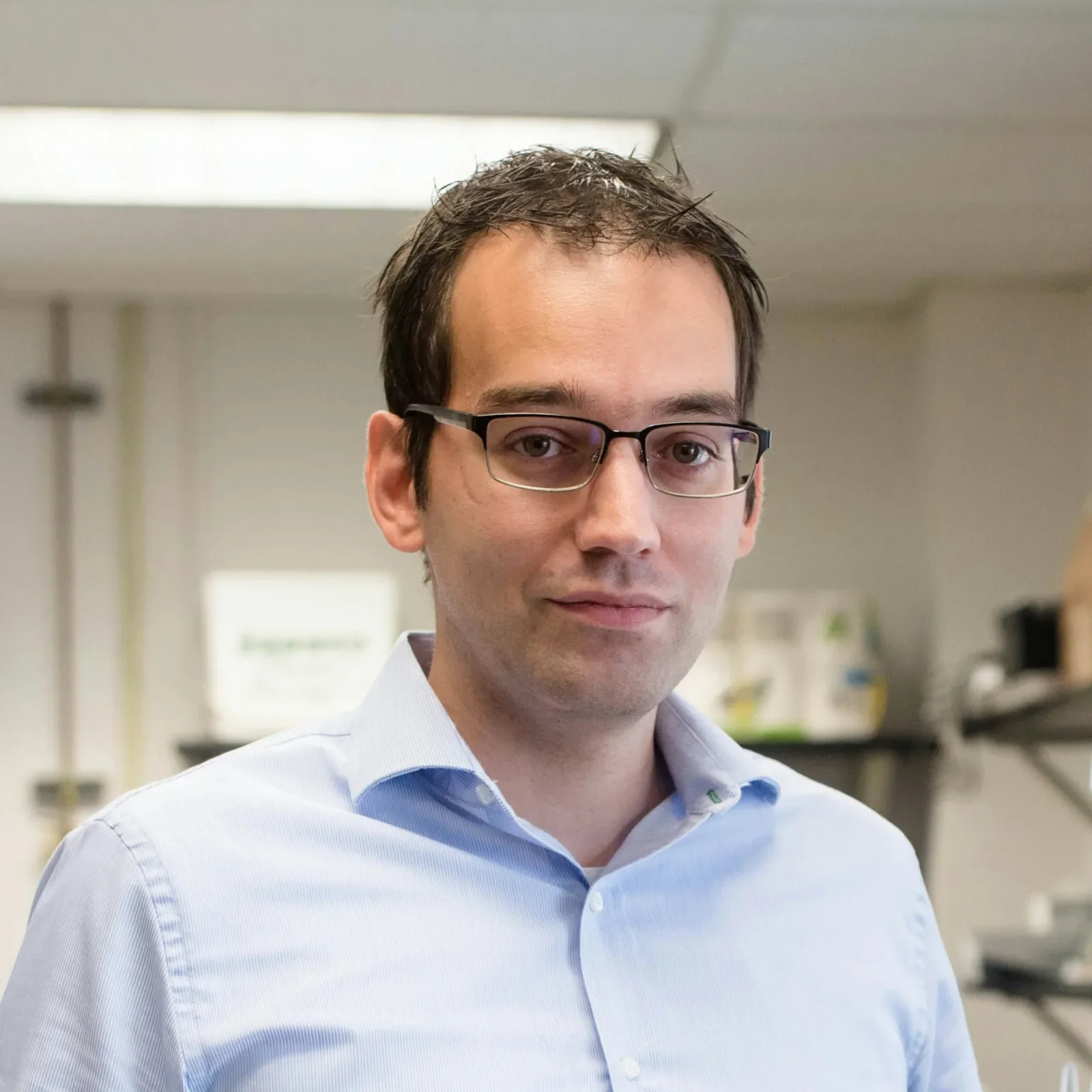 Filippo Mangolini, with a gentle smile, wears glasses and a blue button-up shirt.