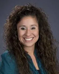 Tracey Flores Headshot with curly hair and a teal shirt