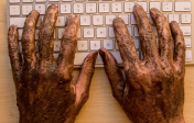 hands covered in mud typing on a keyboard.
