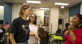 Two individuals talking with a third person listening behind them