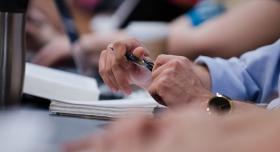 A pair of hands holding a pen and notepad 