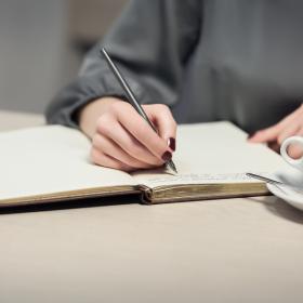 Image of a hand writing into a notebook