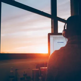Person working at a computer at sunrise