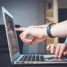 Hands pointing at a laptop computer screen
