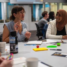 A group of people engaging in a conversationwhile sitting at a table.