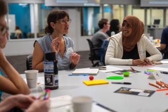 A group of people engaging in a conversationwhile sitting at a table.