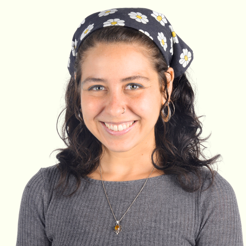 A woman, wearing a grey shirt and flower bandana, who is smiling.