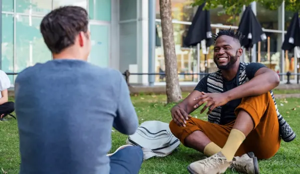 Two men sitting on a lawn, chatting