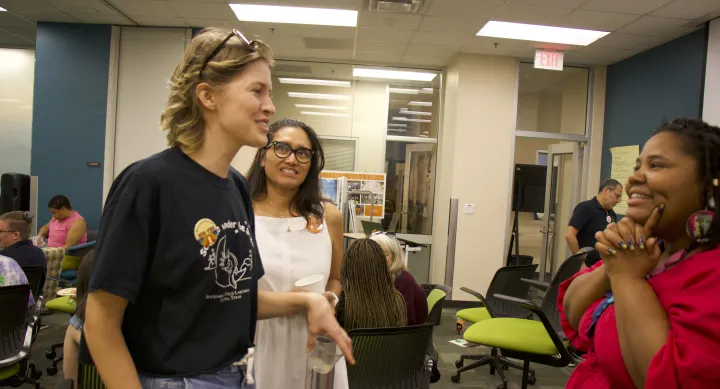Two individuals talking with a third person listening behind them