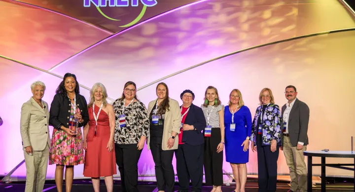 A group of people standing in front of a backdrop that has the acronym NHETC