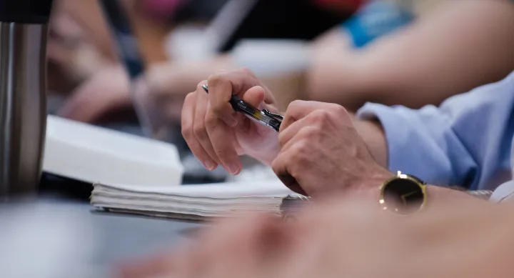 A pair of hands holding a pen and notepad 