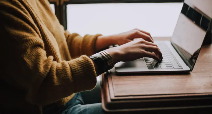 Person's hands typing on a laptop