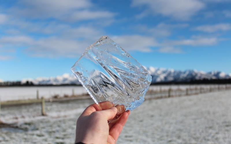 a hand holds out a square piece of ice